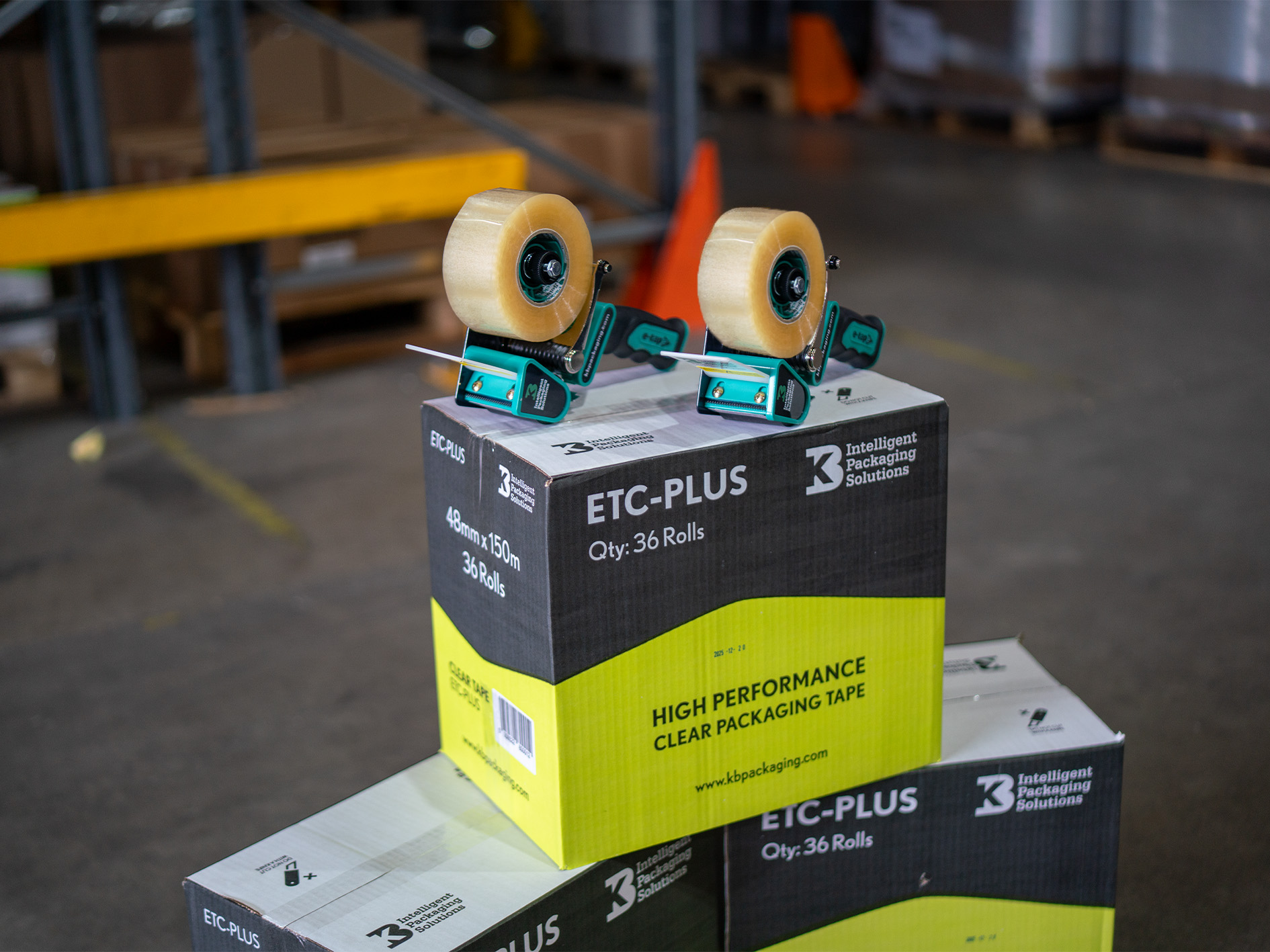 Two E-Tape Dispeners on a pyramid of boxes, within a warehouse background