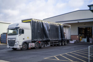 Delivery truck at warehouse loading bay handling cardboard boxes in various sizes for posting, shipping, and pallet distribution