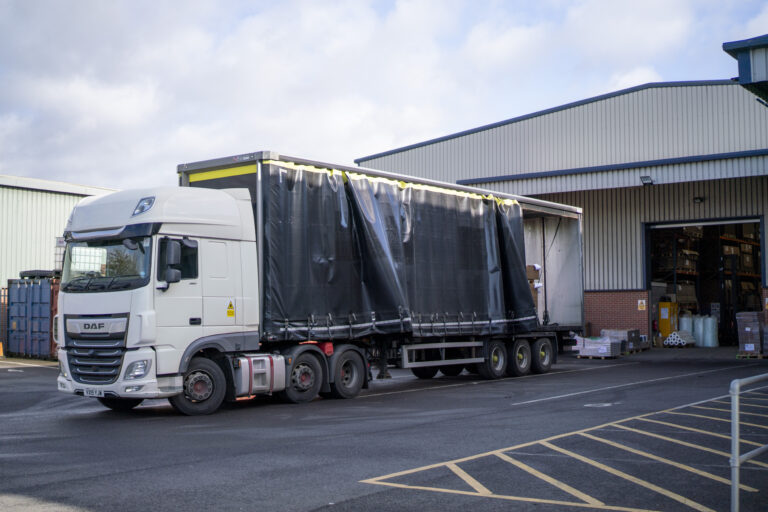 Delivery truck at warehouse loading bay handling cardboard boxes in various sizes for posting, shipping, and pallet distribution