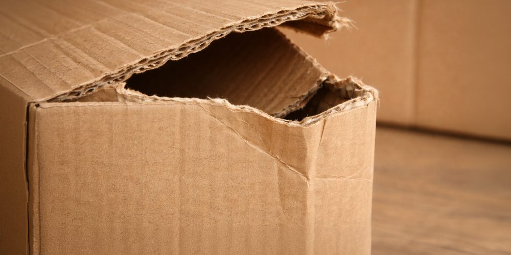 Damaged cardboard box with torn edges and an open flap, showing the impact of poor packaging quality
